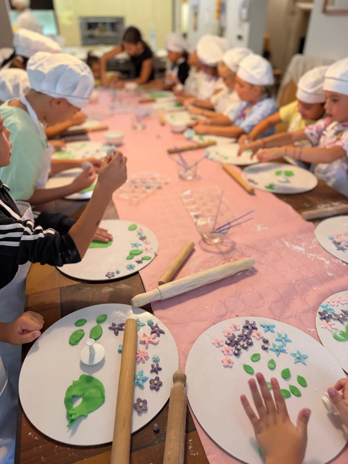Bambini con cappelli da pasticcere durante un laboratorio di decorazione